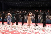 カーペット上になった紙の上で挨拶する登壇者たち。