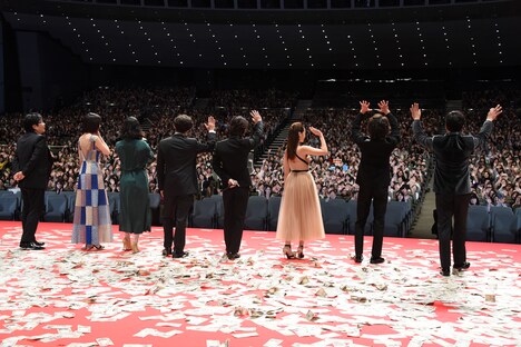 カーペット上になった紙の上で挨拶する登壇者たち。