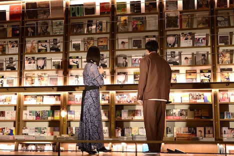 本棚を見渡す黒木華（左）と野村周平（右）。