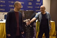 写真撮影に応じている塚本晋也（左）のもとへ近寄り、握手を求めるアミール・ナデリ（右）。