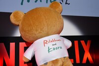 Tシャツ背面のロゴを見せるリラックマ。