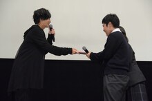 志尊淳（左）から「走れ！T校バスケット部」のフォトブックを受け取る高校1年生の2人組（右）。