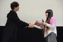 志尊淳（左）から「走れ！T校バスケット部」のフォトブックを受け取るスカイダイバー志望の女性（右）。