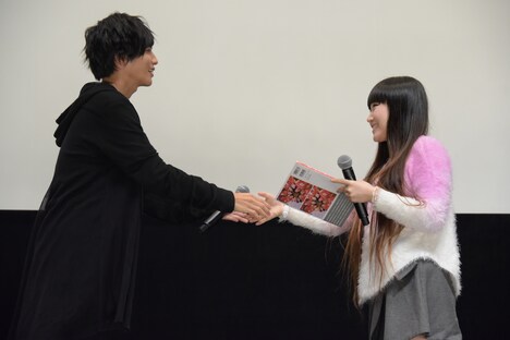 志尊淳（左）から「走れ！T校バスケット部」のフォトブックを受け取るスカイダイバー志望の女性（右）。