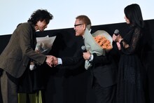 斉藤和義（左）と握手を交わす國村隼（中央）。