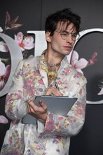 カメラマンを見て、何かをメモするような演技をしてみせるエズラ・ミラー。