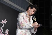 カメラマンを見て、ため息をつきながらメモするような演技をしてみせるエズラ・ミラー。