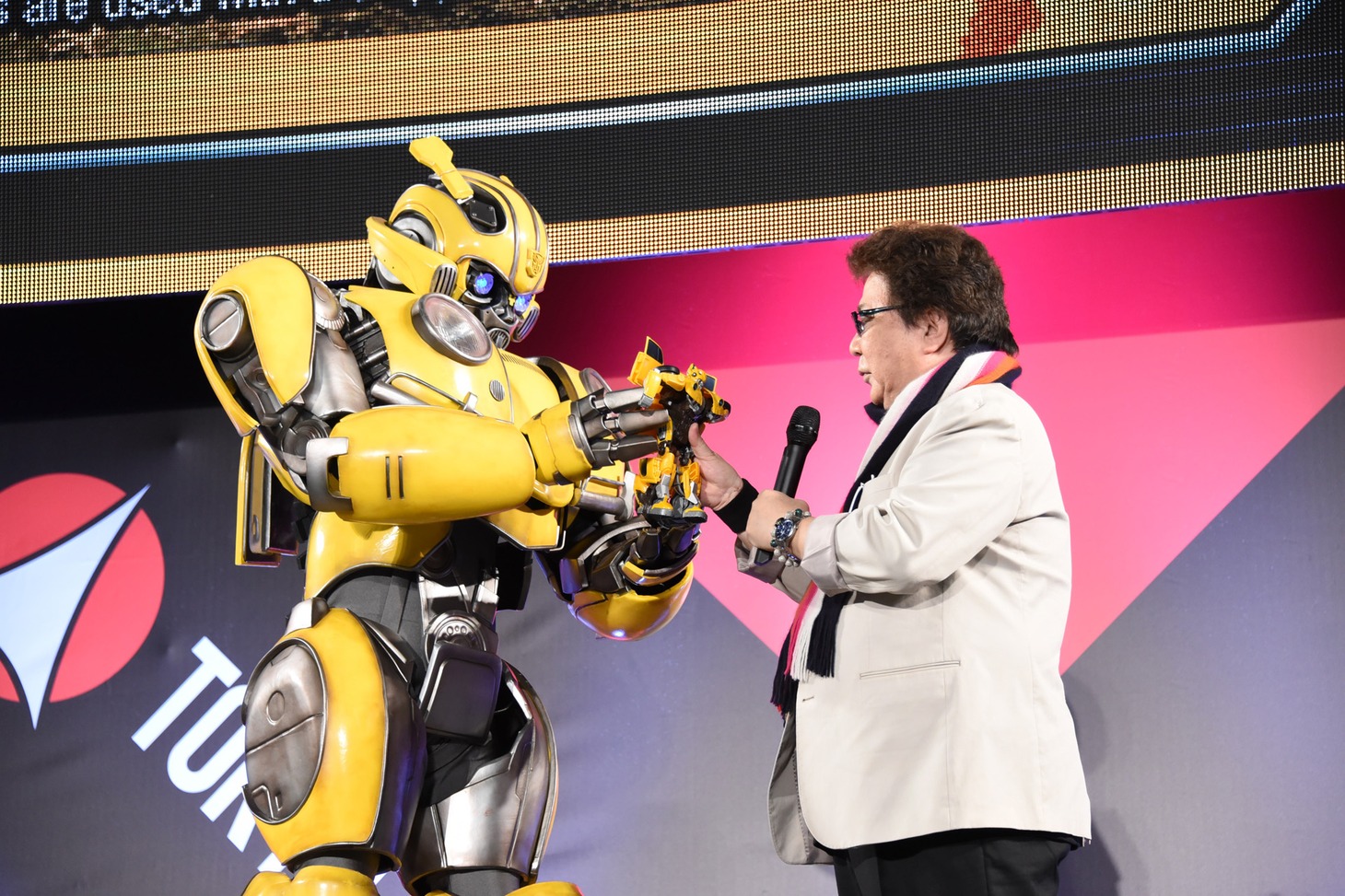 玄田哲章（右）にバンブルビーのおもちゃを手渡すバンブルビー（左）。