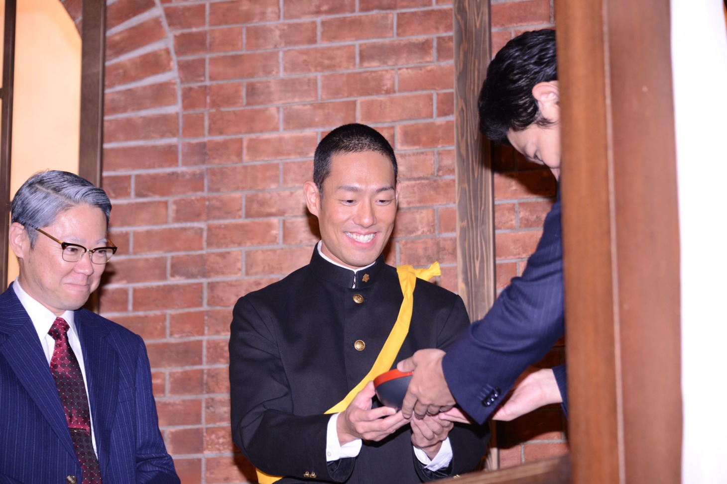 鈴木亮平（右）からさつま揚げを受け取る中村勘九郎（中央）。