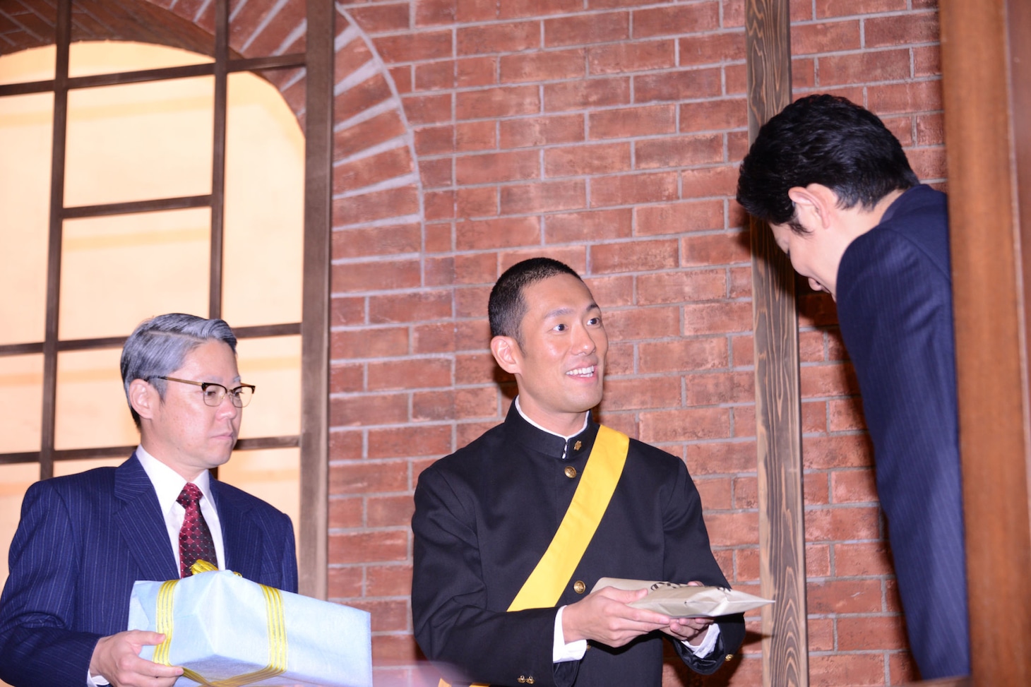 鈴木亮平（右）に特製マラソン足袋を渡す中村勘九郎（中央）。