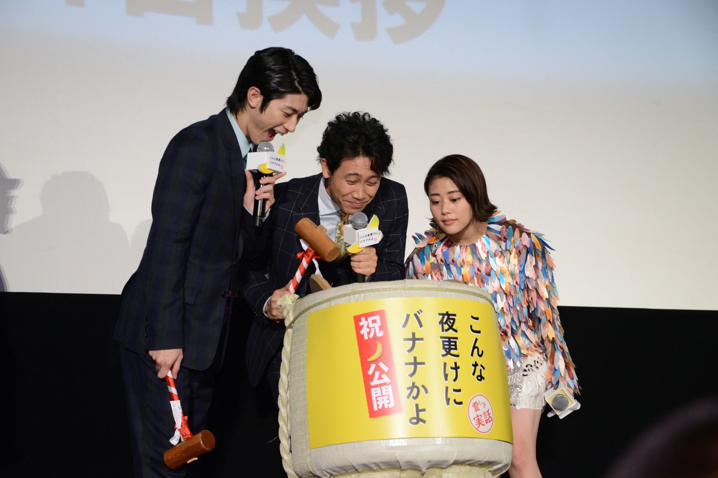 バナナジュースが入った樽をのぞき込む登壇者たち。