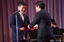 岸善幸（右）から表彰盾を受け取る是枝裕和（左）。