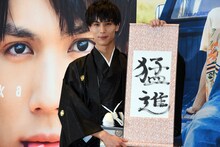 「猛進」としたためた書き初めを持つ中川大志。