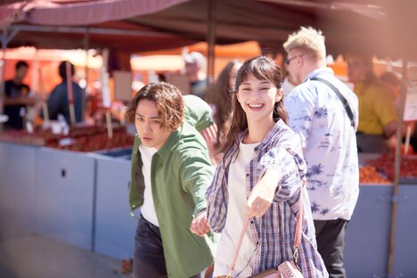 「雪の華」より、マーケット広場で撮影されたシーン。朝市で買い物する悠輔（左）と美雪（右）。