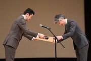 賞状を受け取る佐藤英之氏（右）。