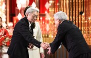 細野晴臣(左)が、2018年の受賞者・鈴木慶一(右)と握手を交わす様子。