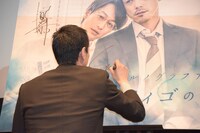 パネルにサインをする吉田宗洋。