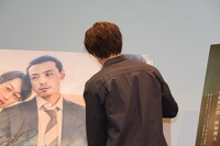 パネルにサインをする猪塚健太。