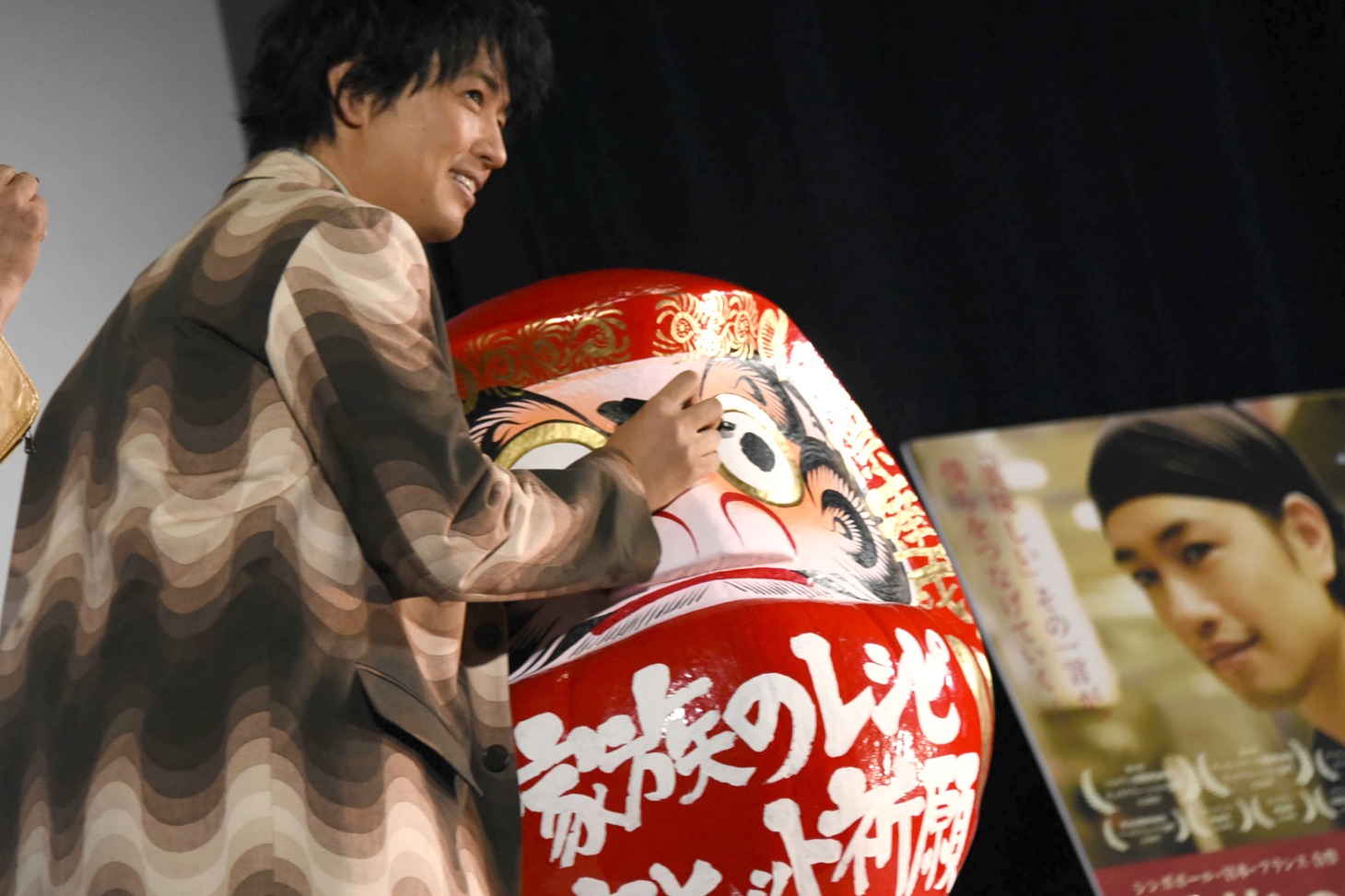 斎藤工がだるまの目を披露する様子。