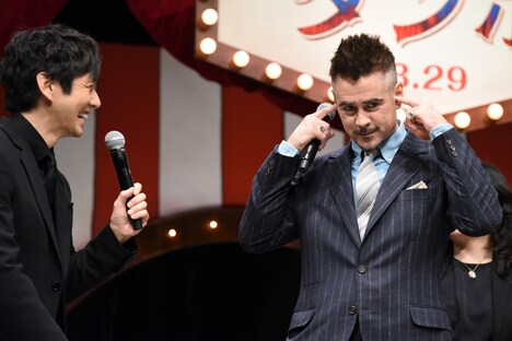 西島秀俊（左）が自分の話をすることを知り、耳をふさぐコリン・ファレル（右）。