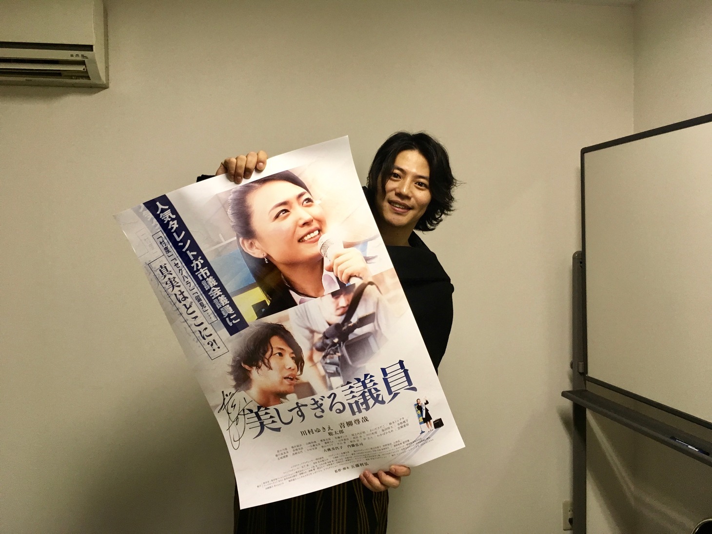 「美しすぎる議員」のポスターを持つ青柳尊哉
