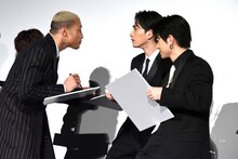 町田啓太（中央）を凝視しながら白石聖の似顔絵を描く関口メンディー（左）。