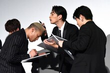 関口メンディー（左）の頭皮を見ながら、白石聖の似顔絵を描く町田啓太（中央）。