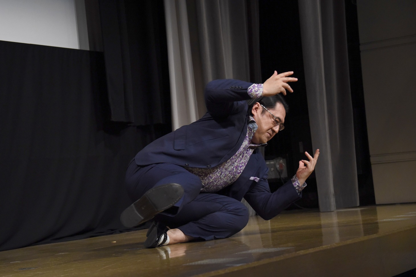 撮影時にがんばったものの本編には使われなかったという、“手を使わずに立ち上がる”動きを再現する小手伸也。