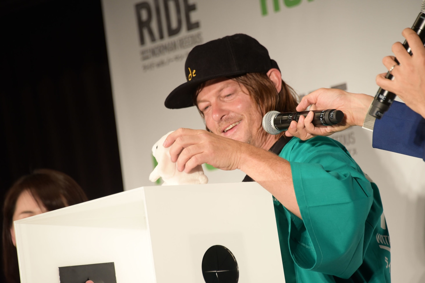 箱の中から出てきたウサギのぬいぐるみを見つめるノーマン・リーダス。