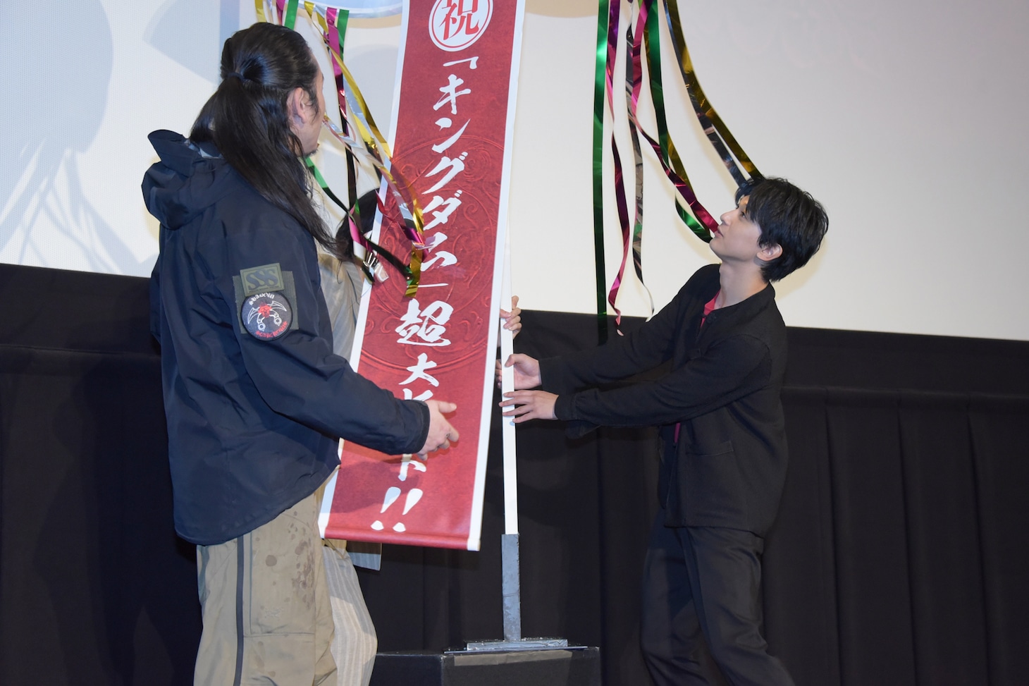 報道陣のためにくす玉を動かすキャストたち。