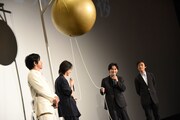 山崎賢人と吉沢亮が、くす玉の紐の引っ張り方を相談する様子。