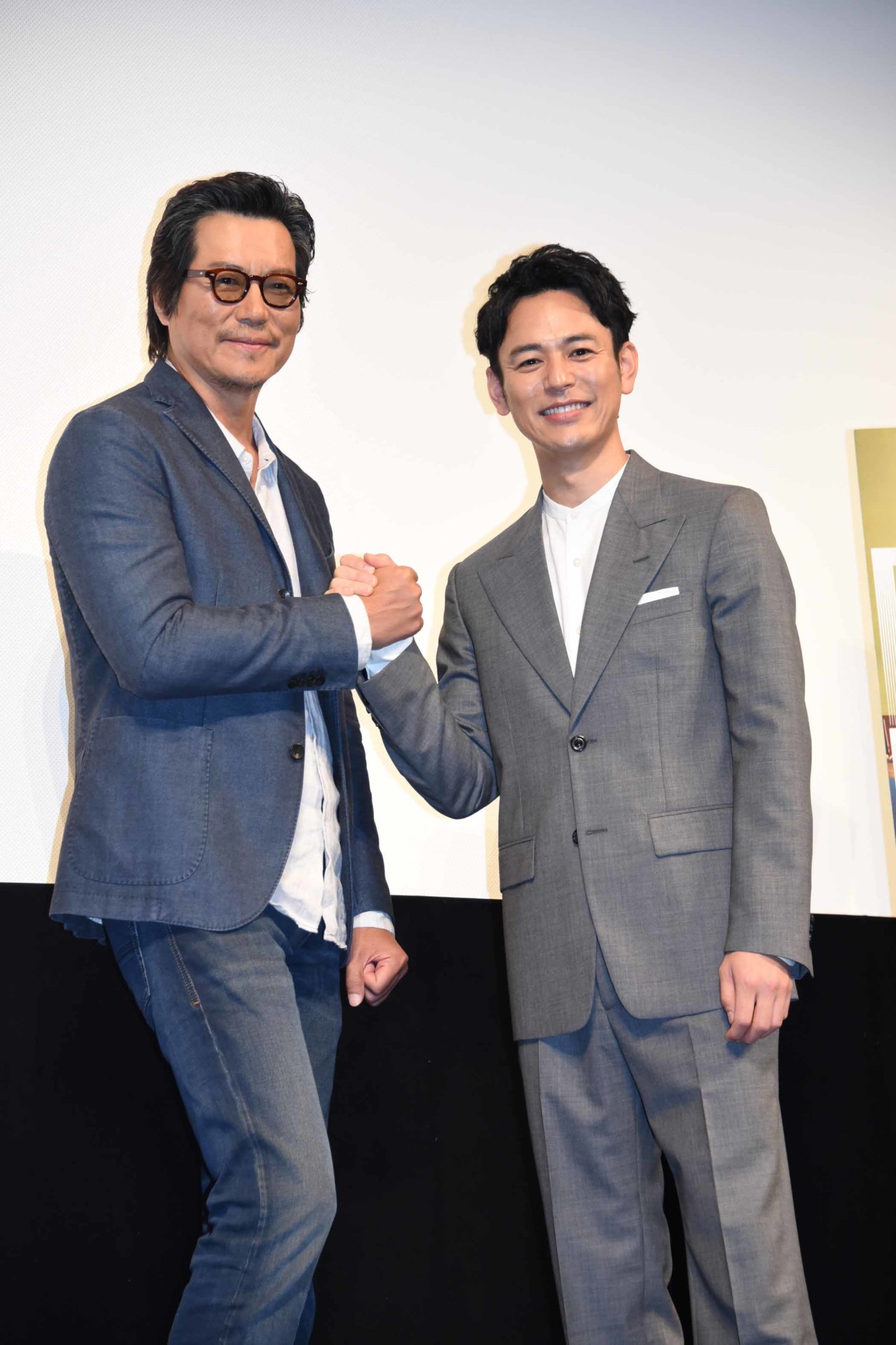 握手を交わす豊川悦司（左）と妻夫木聡（右）。