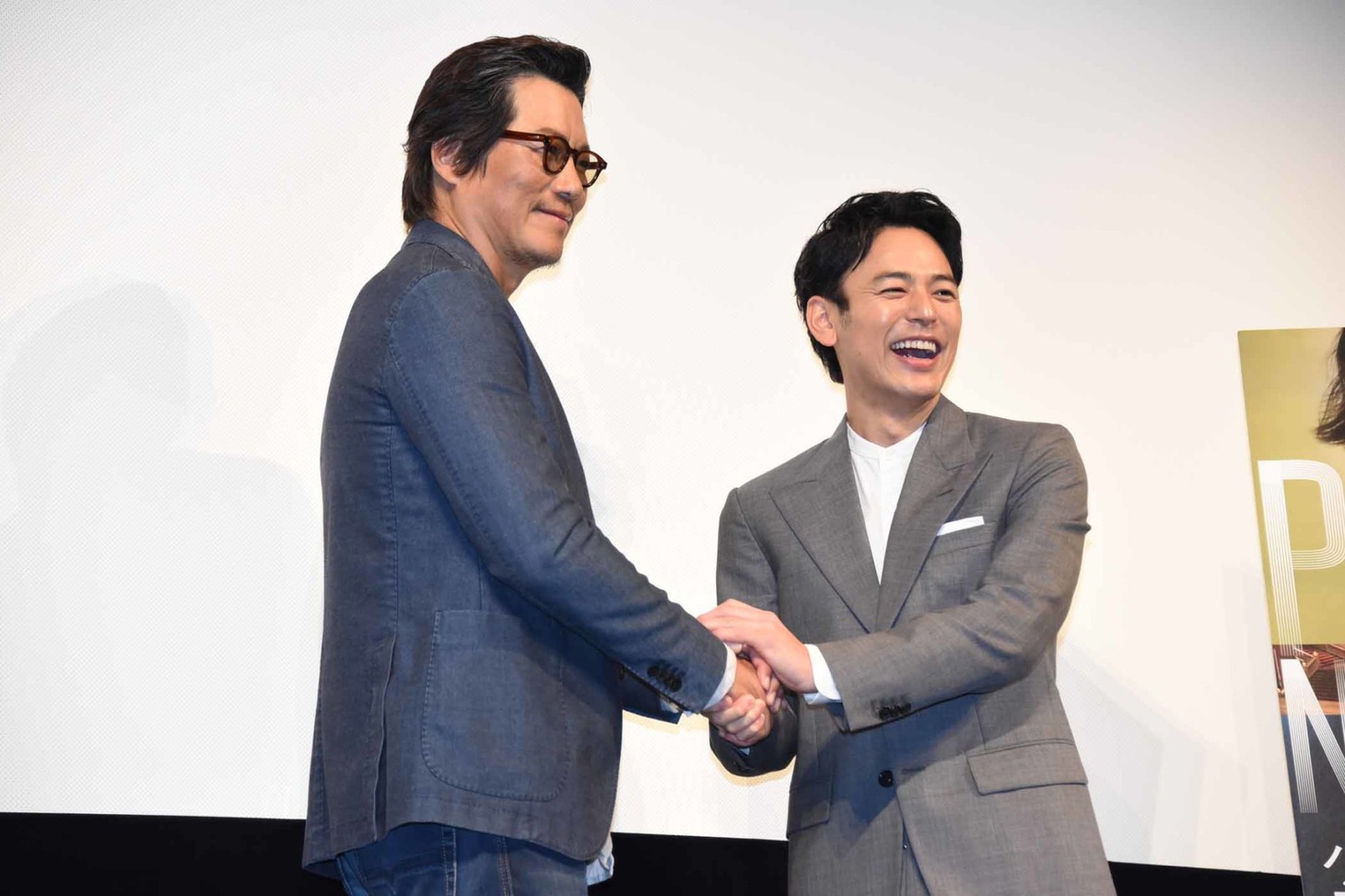 豊川悦司（左）と握手しながら「業務提携!?」と言って笑う妻夫木聡（右）。