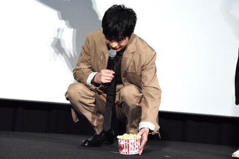 ライブビューイングカメラに手を振るため、ポップコーンを置く田中圭。