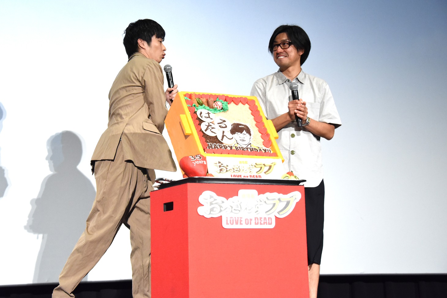カメラに手を振らずによそ見している瑠東東一郎（右）を、はたく田中圭（左）。