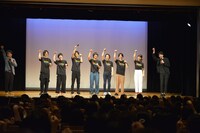 聡太郎（右端）の発声に合わせてシャムニャーンのポーズを取る登壇者たちと観客。