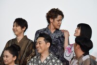 フォトセッション中、背が低いため宮野真守（後列中央）の肩につかまって背伸びをしていた沢城みゆき（後列右）。