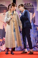 emma（左）の着るトレンチコートに興味津々の飯豊まりえ（右）。