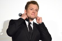 デクスター・フレッチャーに褒められている間、耳をふさぐタロン・エジャトン。