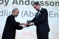 審査員の塚本晋也（左）からロイ・アンダーソンに代わってトロフィーを受け取る「About Endlessness（英題）」のプロデューサー、ヨハン・カールソン（右）。（写真提供：Marechal Aurore / ABACA / Newscom / ゼータ イメージ）