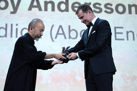 審査員の塚本晋也(左)からロイ・アンダーソンに代わってトロフィーを受け取る「About Endlessness(英題)」のプロデューサー、ヨハン・カールソン(右)。(写真提供:Marechal Aurore / ABACA / Newscom / ゼータ イメージ)