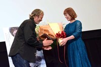 佐藤仁美（右）から花束を受け取るマッツ・ミケルセン（左）。