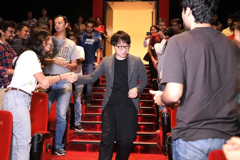 観客と握手をしながらステージへと向かう新海誠(中央)。