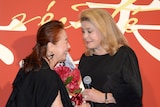 カトリーヌ・ドヌーヴ(右)に花束を渡す宮本信子(左)。