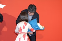 佐々木みゆ（手前）から花束をもらう是枝裕和（奥）。