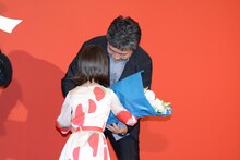 佐々木みゆ（手前）から花束をもらう是枝裕和（奥）。
