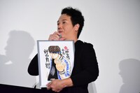 高橋ヒロシのイラスト原画を持って登壇したやべきょうすけ。
