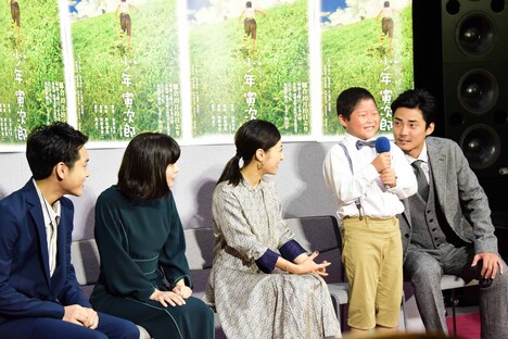 藤原颯音（中央右）を見守る共演者たちと、隣からささやく毎熊克哉（右）。