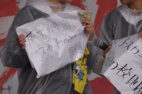 制服への思いを書いたプラカードを掲げる女子高校生。