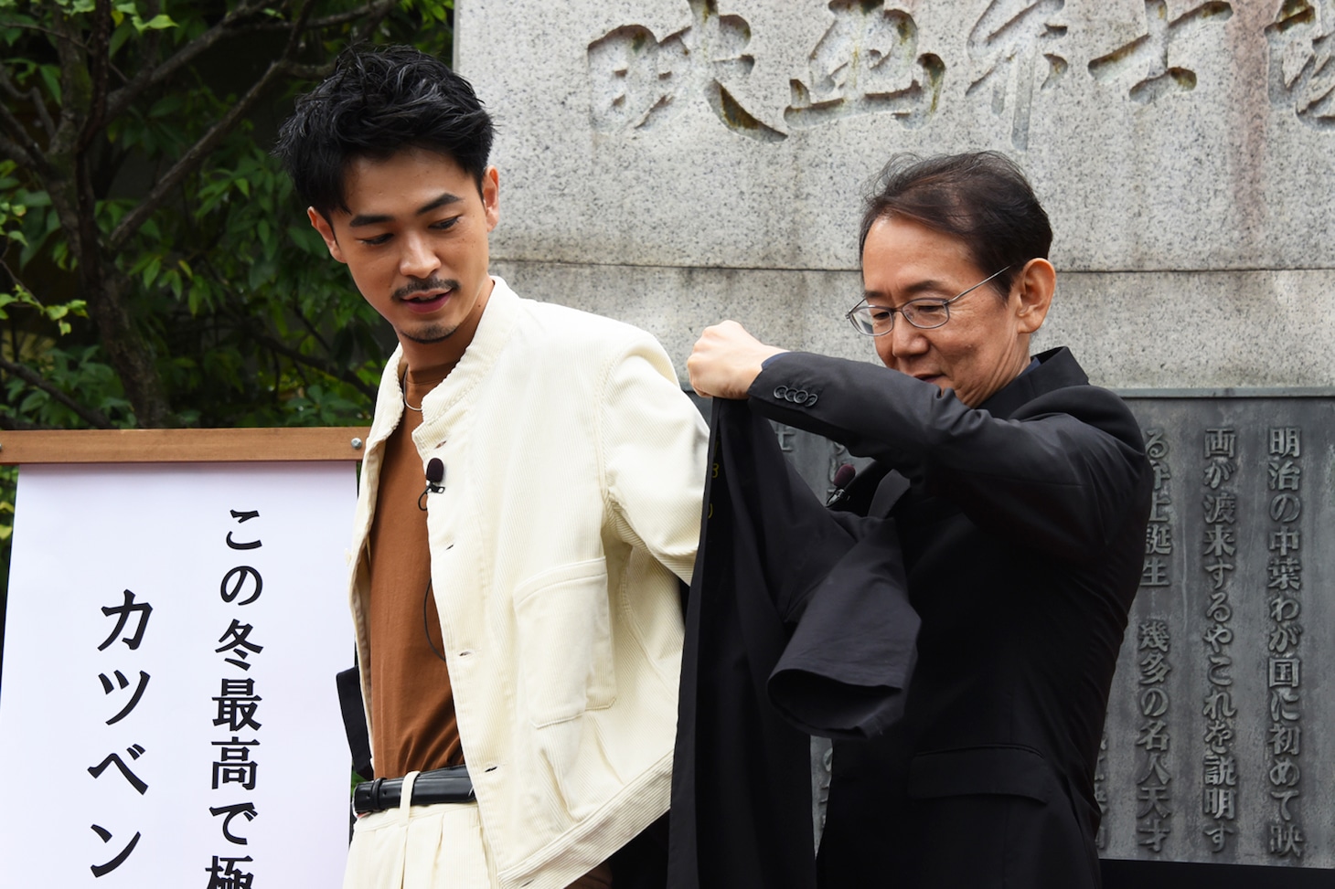 成田凌（左）に法被を着せる周防正行（右）。